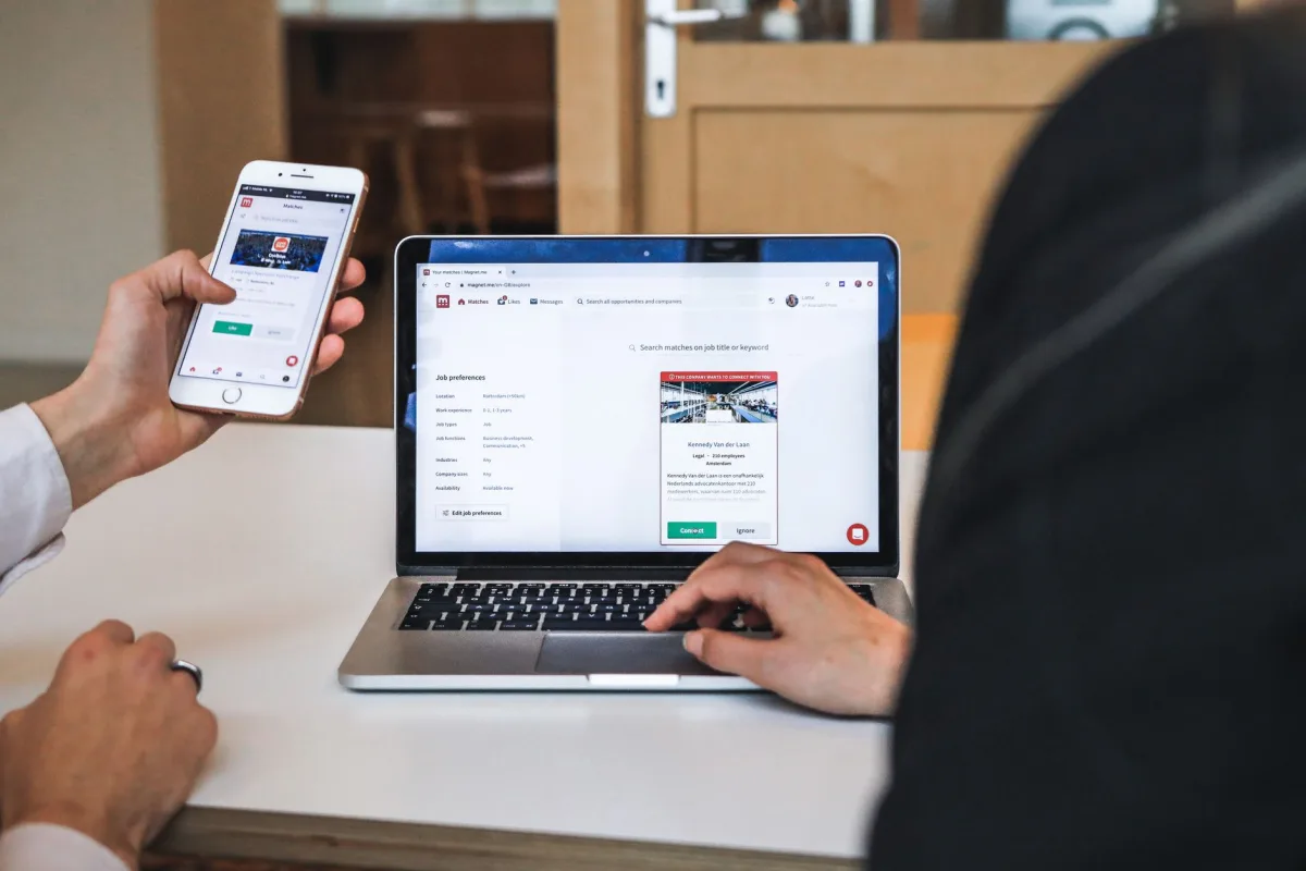 People comparing a website on a smartphone and laptop while completing an online task