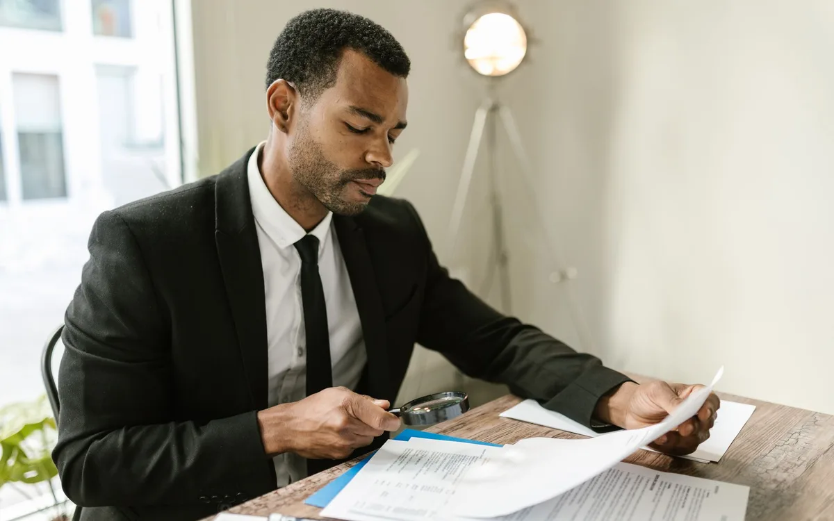 Professional reviewing business documents with a magnifying glass before approving a source correction