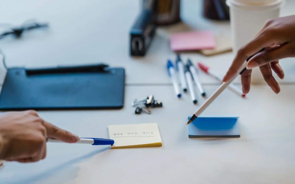 Two people organizing content ideas with notes and pens on a desk