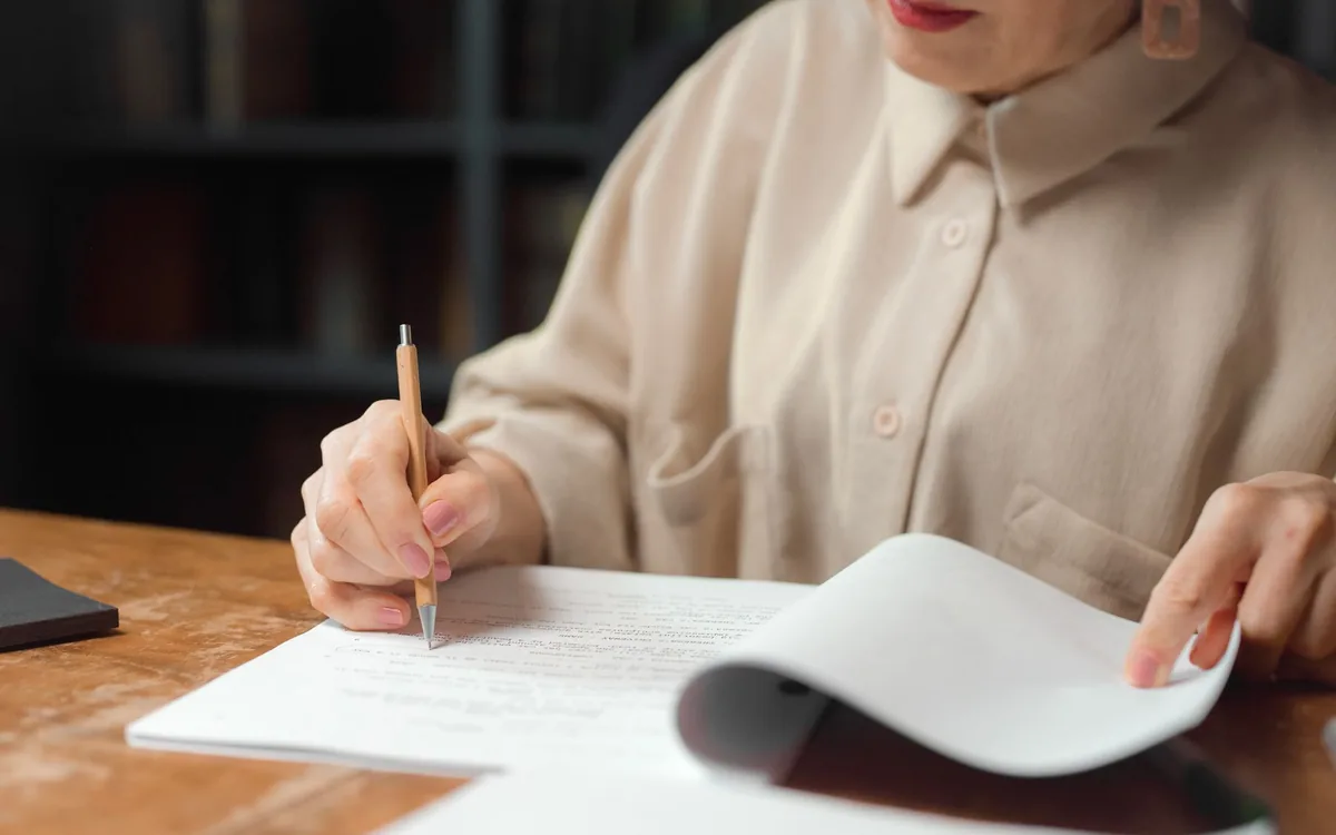 An editor carefully marking a printed draft with a pencil